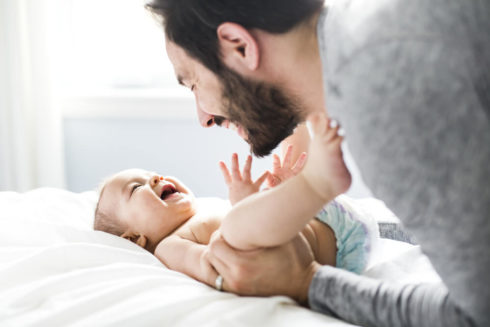 a-happy-father-playing-with-adorable-baby-in-bedroom_575
