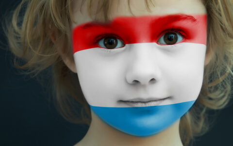 Portrait of a child with a painted flag of Luxembourg on her face, closeup.