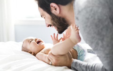 A-happy-father-playing-with-adorable-baby-in-bedroom